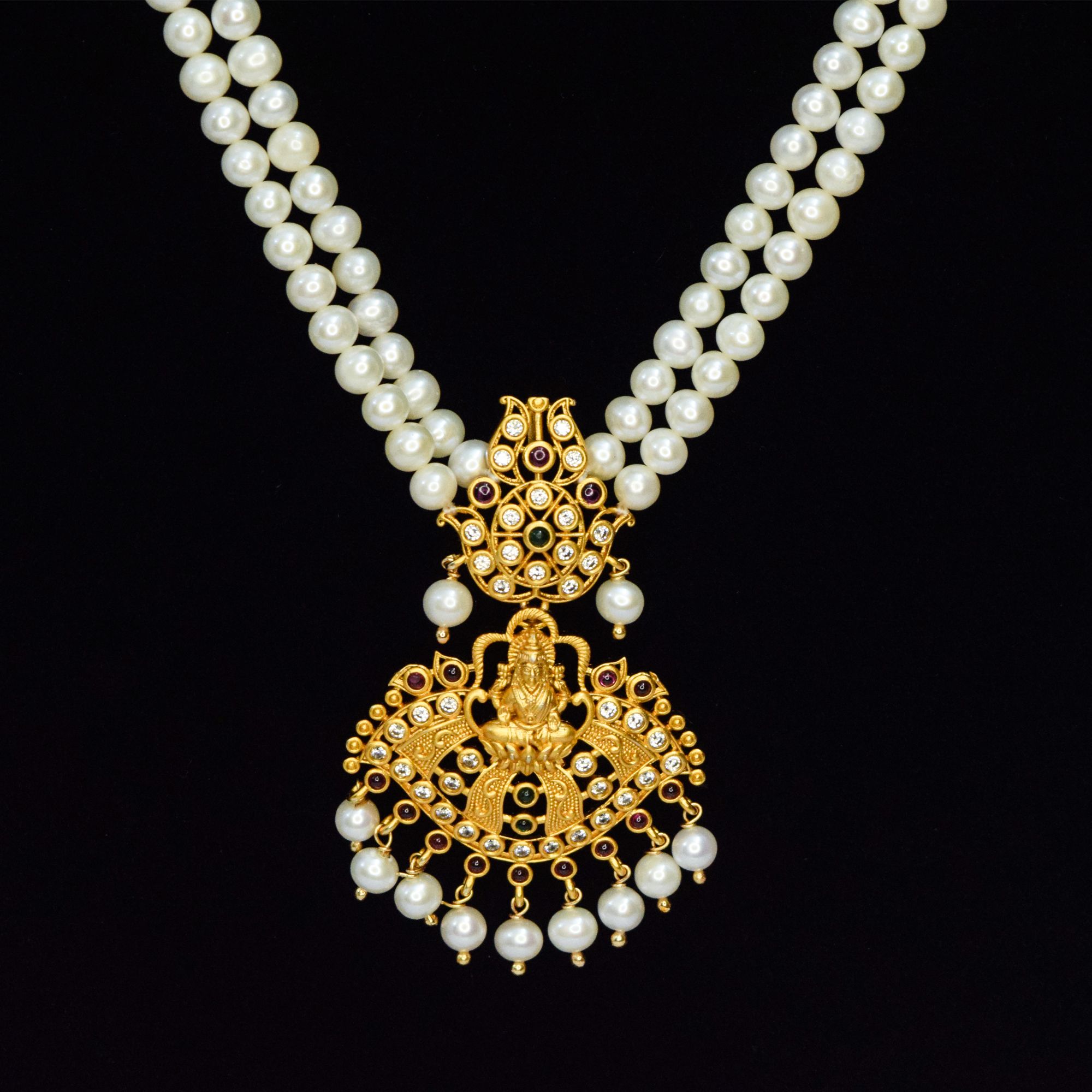 Two-row rich white round pearl long necklace with a traditional matt finish Lakshmi pendant studded with zircons, semi-precious Rubies & Emerald - close up
